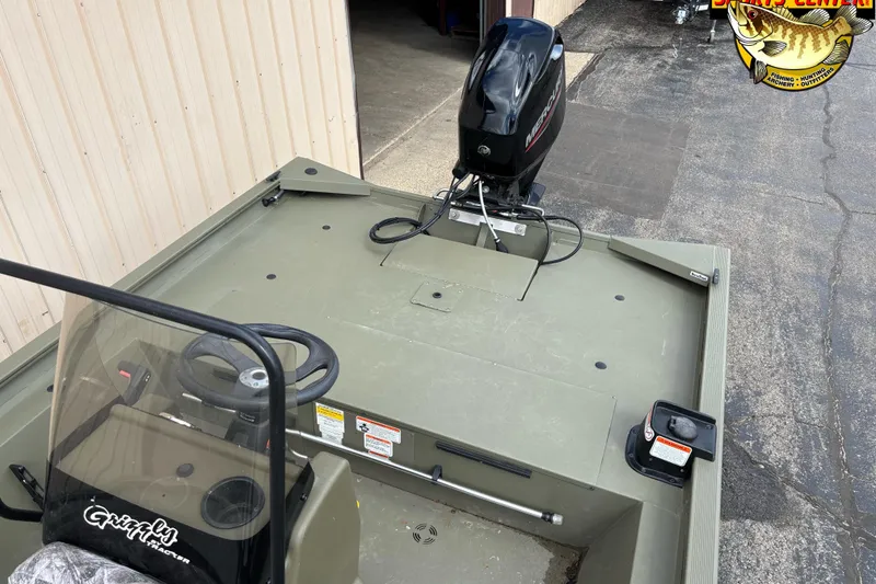 Slide: The Image of 2023 Tracker Grizzly 1860 CC boat with Mercury outboard motor, parked near a building. - 7