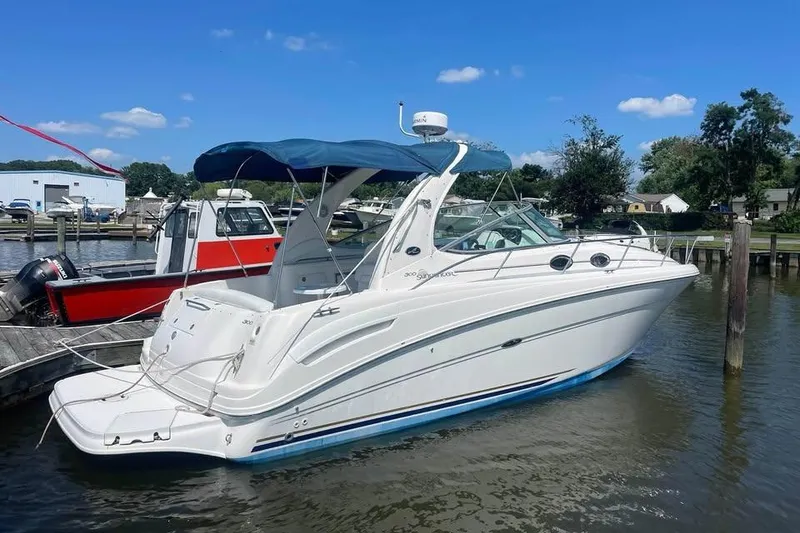 Slide: The Image of 2003 Sea Ray 300 Sundancer boat docked in a marina under a clear blue sky. - 1
