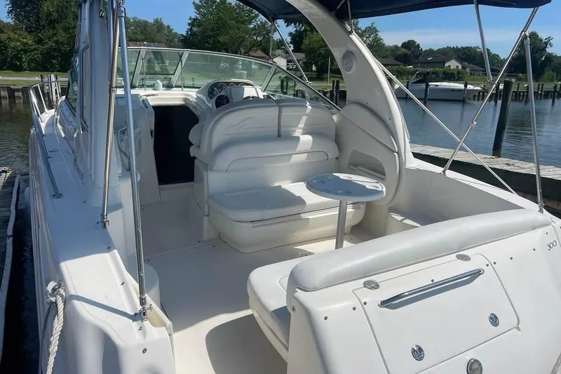 Slide: The Image of 2003 Sea Ray 300 Sundancer boat with white seating and table, docked by a marina. - 5