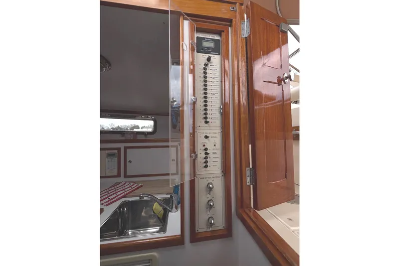 Slide: The Image of Electrical panel inside 2001 Bluestar BlueStar 29.9 boat, featuring wooden cabinetry and stainless steel sink. - 23
