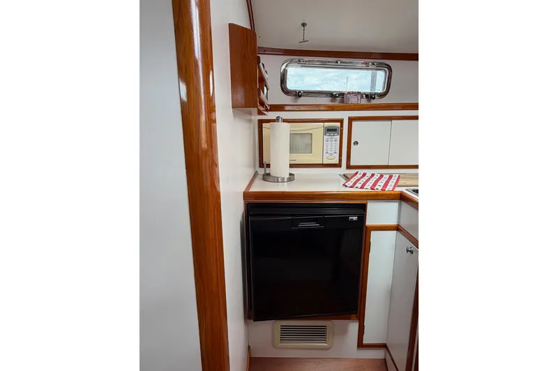 Slide: The Image of Compact kitchen area in a 2001 Bluestar BlueStar 29.9 boat, featuring wood accents and appliances. - 19