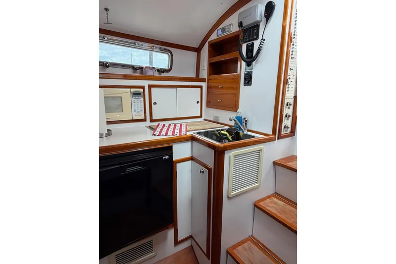 Slide: The Image of Compact kitchen area in a 2001 Bluestar BlueStar 29.9 boat, featuring wood accents and appliances. - 20