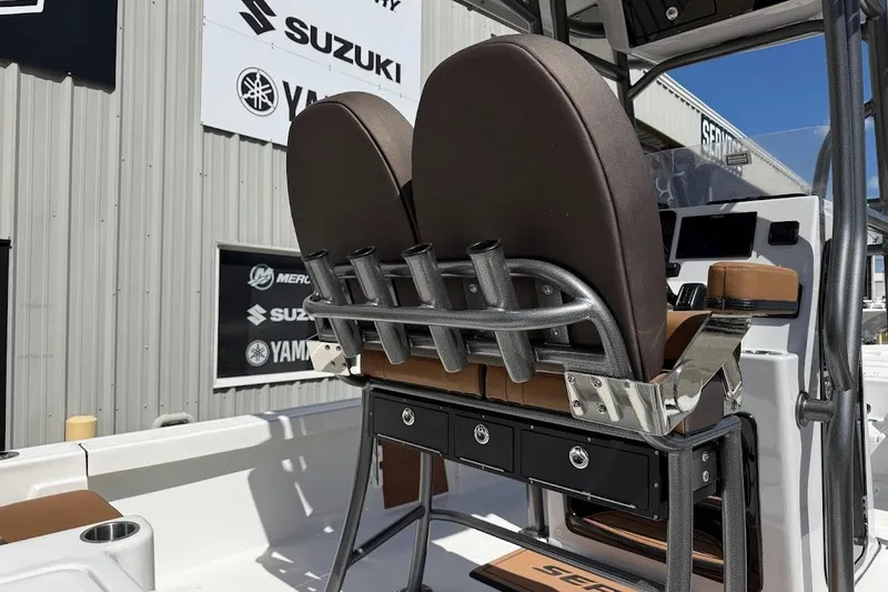 Slide: The Image of 2026 Sea Pro 230 Bay boat interior with rod holders and seating, displayed at a dealership. - 9