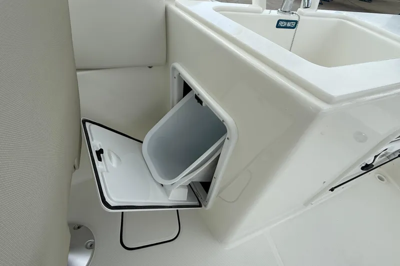 Slide: The Image of 2026 World Cat 230 SD boat interior with open storage compartment and fresh water sink. - 23