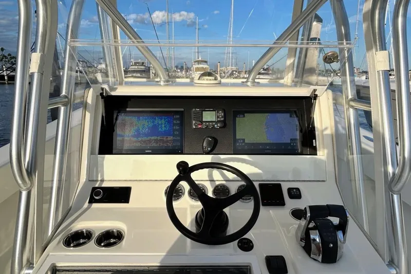Slide: The Image of 2020 SeaVee 370Z boat helm with navigation screens and steering wheel in marina setting. - 11