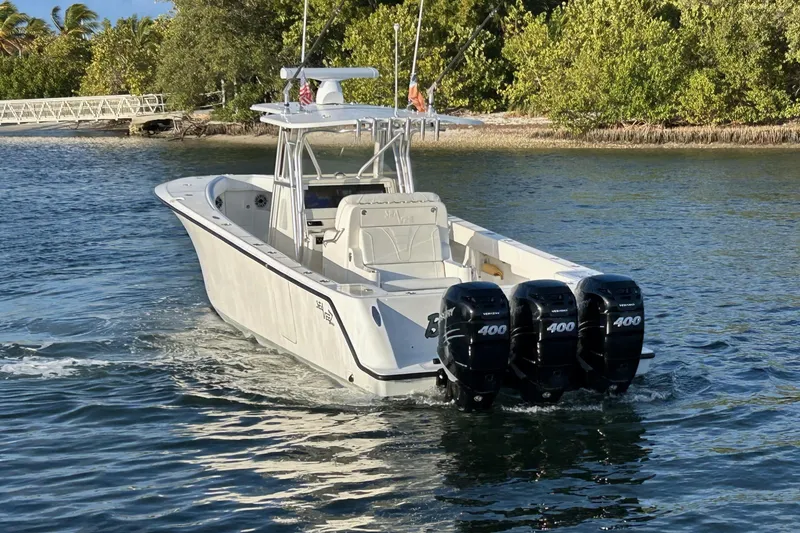 Slide: The Image of 2020 SeaVee 370Z boat with triple 400 horsepower engines cruising near a lush shoreline. - 7