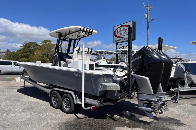 Slide: The Image of 2024 Tidewater 2700 Carolina Bay boat on trailer, featuring dual Mercury engines. - 2