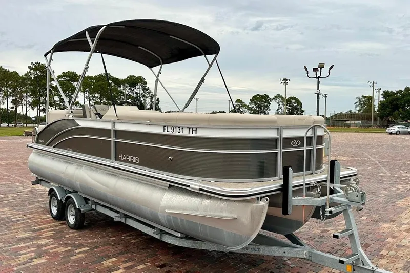 The Image of 2023 Harris Cruiser 230 pontoon boat on trailer in parking lot. - 1