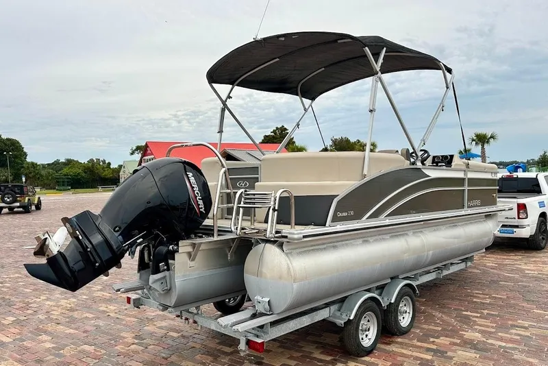 Slide: The Image of 2023 Harris Cruiser 230 pontoon boat on trailer with Mercury outboard motor. - 2