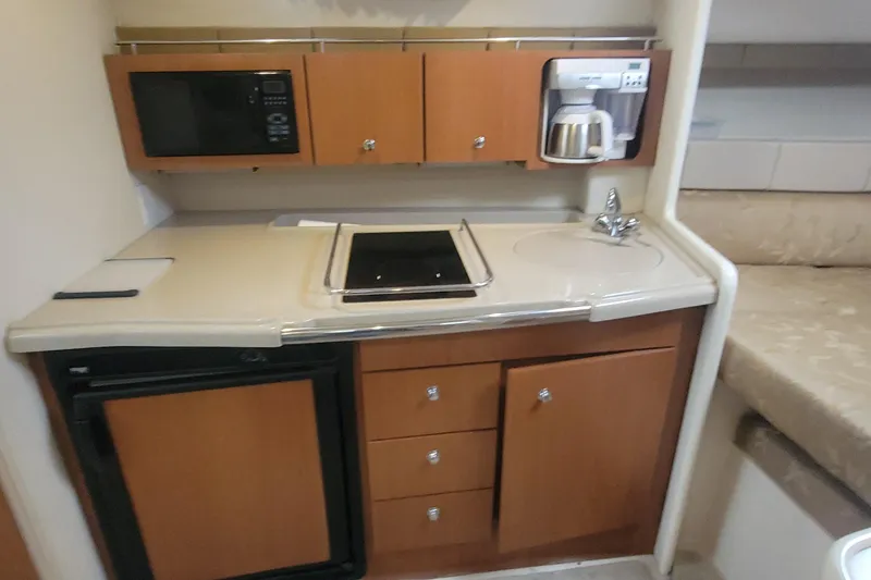 Slide: The Image of Compact kitchen area in a 2006 Wellcraft 330 Coastal boat, featuring appliances and storage. - 12