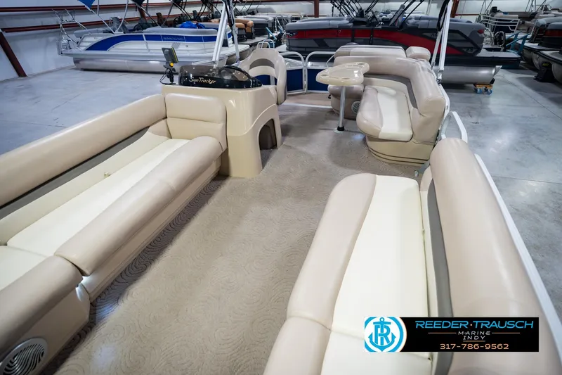 Slide: The Image of 2014 Sun Tracker Party Barge 20 DLX interior with beige seating in a showroom. - 12