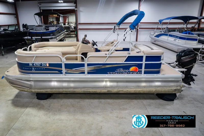 The Image of 2014 Sun Tracker Party Barge 20 DLX pontoon boat in showroom, featuring Mercury outboard motor. - 2