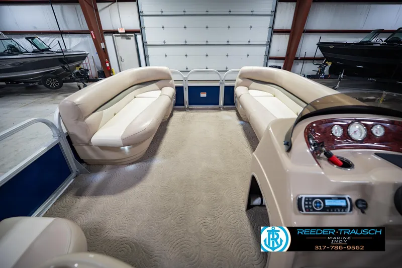 Slide: The Image of 2014 Sun Tracker Party Barge 20 DLX interior with beige seating and control panel in a showroom. - 20