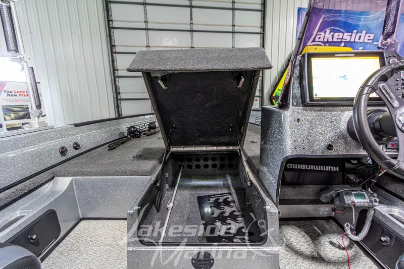 Slide: The Image of Interior of a 2019 Recon 2185 SC boat with open storage compartment and navigation equipment. - 26
