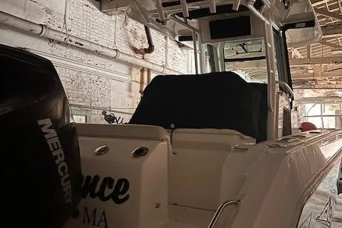 Slide: The Image of 2022 Boston Whaler 250 Outrage boat in a warehouse, featuring a Mercury engine. - 13