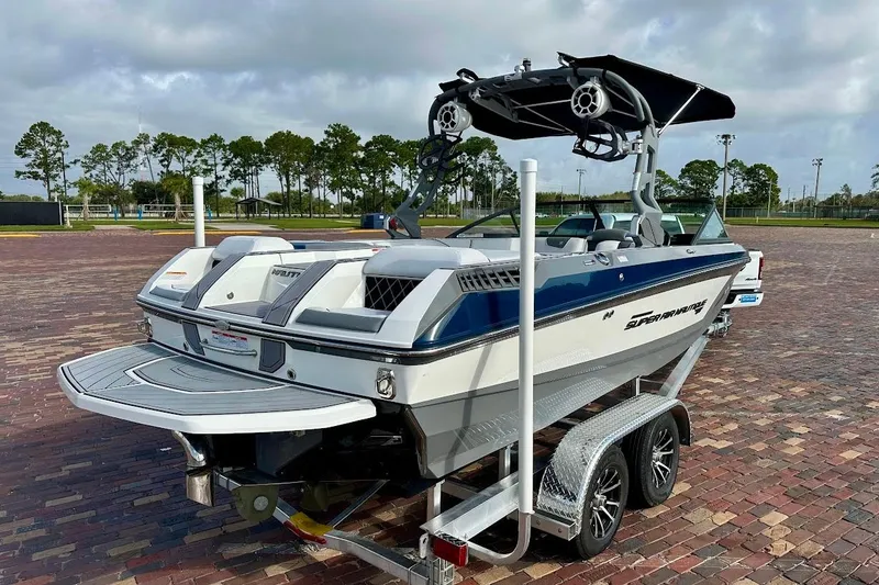 Slide: The Image of 2018 Nautique Super Air Nautique GS22 boat on trailer, parked on brick pavement. - 2