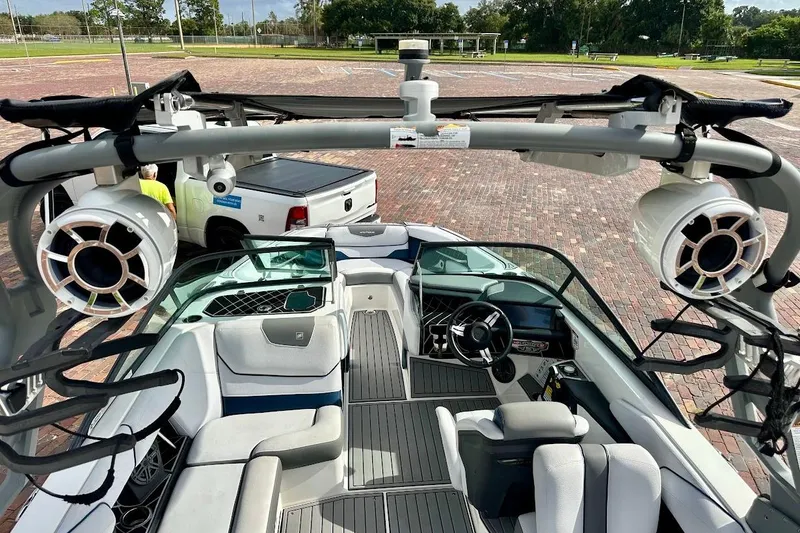 Slide: The Image of 2018 Nautique Super Air Nautique GS22 boat interior with speakers and seating, parked on brick pavement. - 26