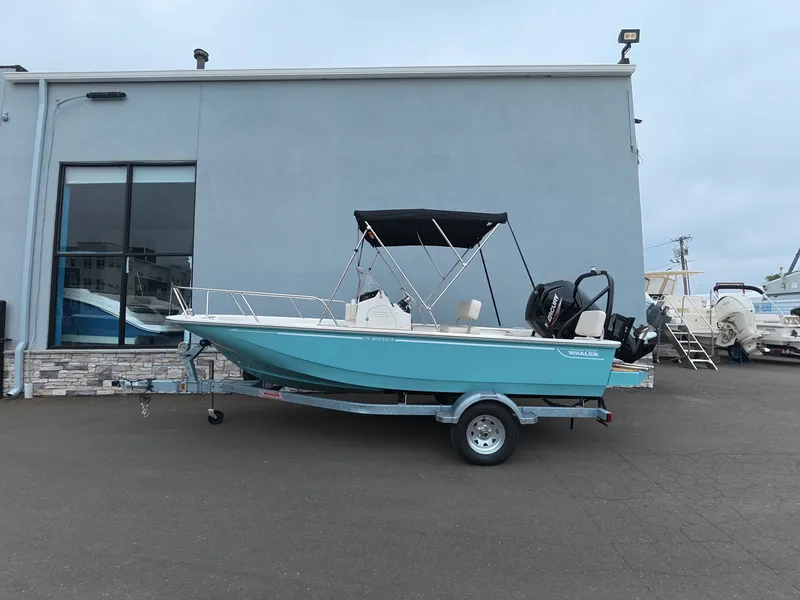 Slide: The Image of A 2027 Boston Whaler 170 Montauk on a trailer outside a building. - 0