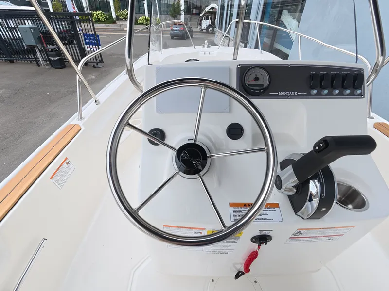 Slide: The Image of The image shows the helm of a Boston Whaler 170 Montauk with a stainless steel wheel and instruments. - 14