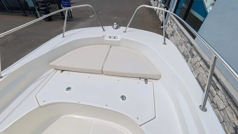 Slide: The Image of The image shows the bow of a 2027 Boston Whaler 170 Montauk with white cushions and stainless steel railing. - 24