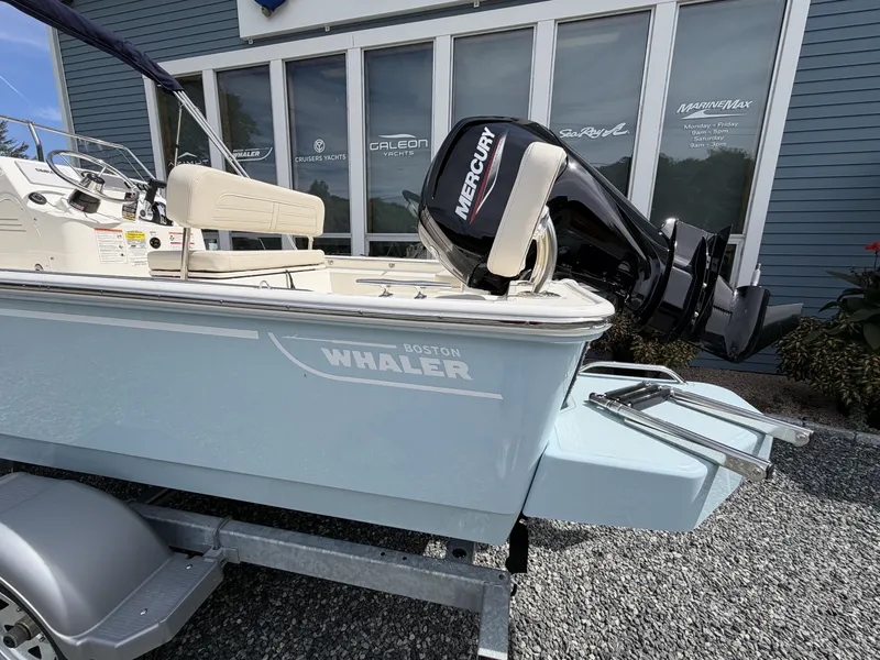 Slide: The Image of Boston Whaler 170 Montauk 2027 with Mercury outboard motor, on a trailer in front of a building. - 2