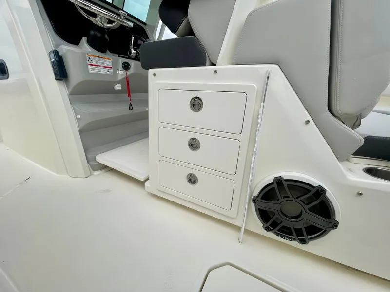 Slide: The Image of The interior view shows drawers and a speaker on a 2027 Boston Whaler 330 Outrage. - 15