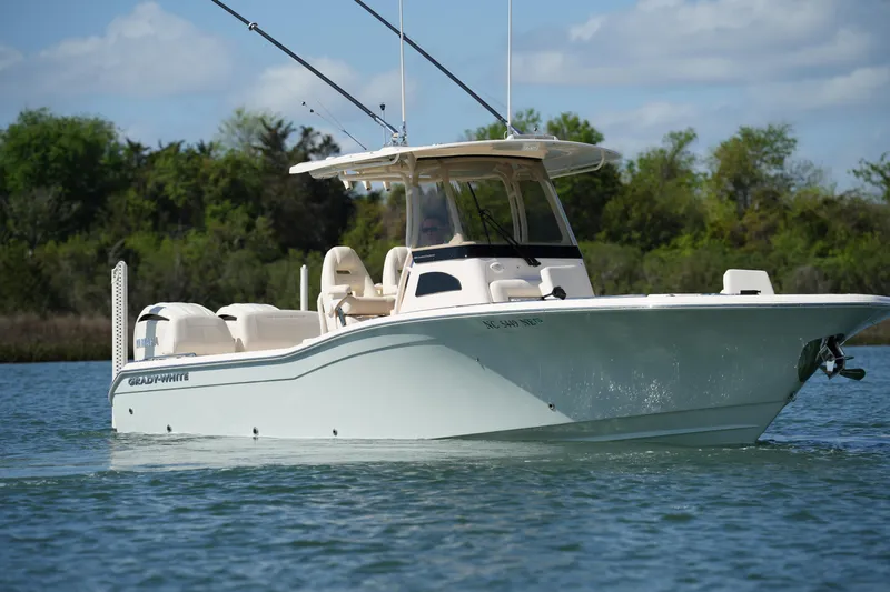 Slide: The Image of 2025 Grady-White 281 Coastal Explorer boat on calm water, surrounded by greenery. - 2