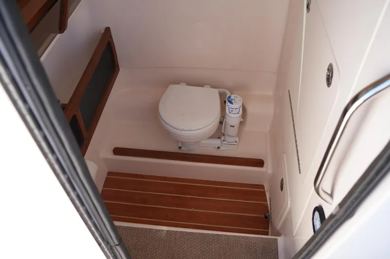 Slide: The Image of 2025 Grady-White 281 Coastal Explorer boat bathroom with wooden flooring and compact toilet. - 36
