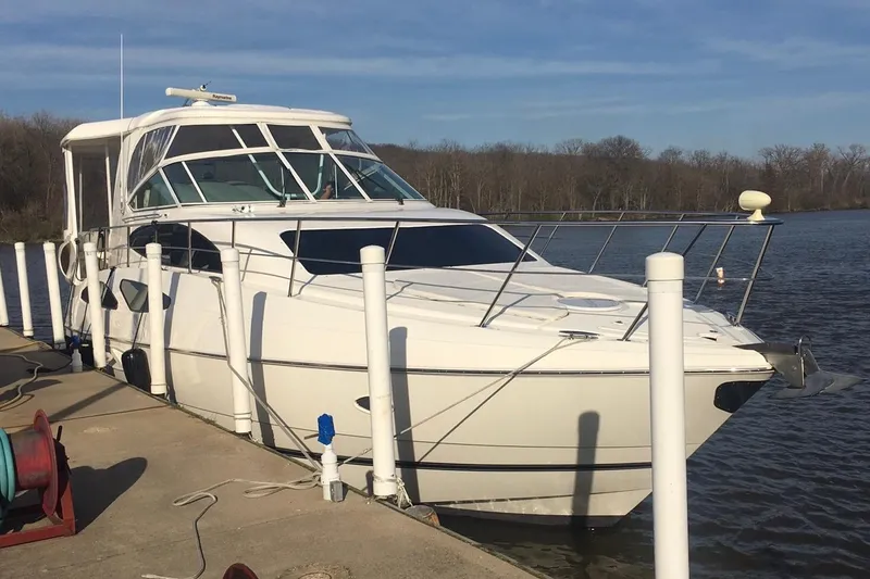 Slide: The Image of 2004 Cruisers Yachts 455 Express Motoryacht docked by a serene riverbank. - 4