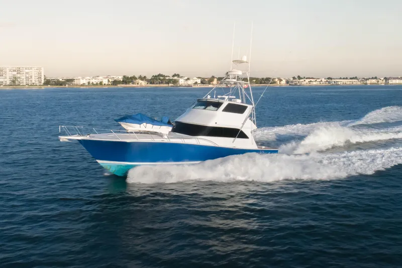 Slide: The Image of 2003 Viking 65 EB yacht cruising on open water near coastal buildings. - 1