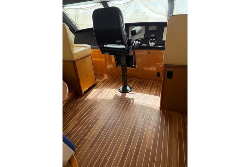 Slide: The Image of Pilot seat and control panel inside 2003 Viking 65 EB yacht with wooden flooring. - 23