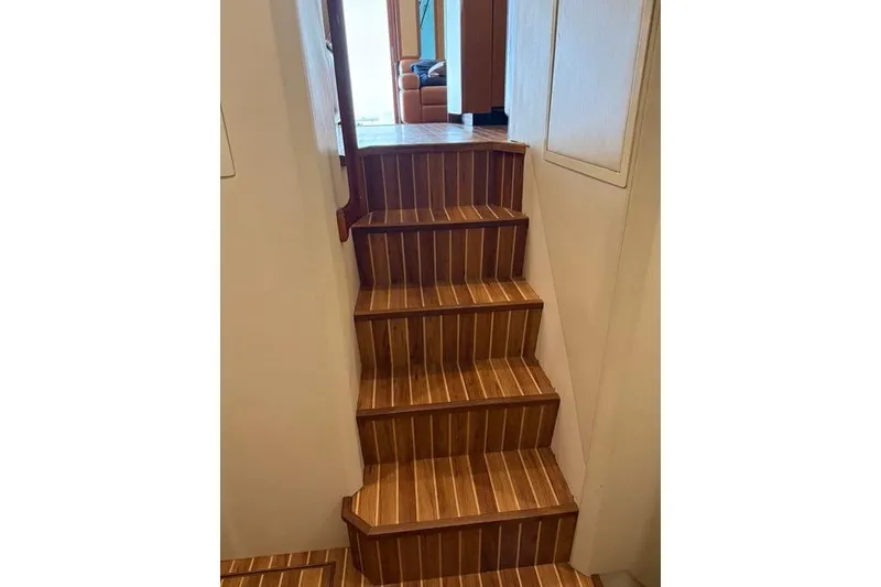 Slide: The Image of Wooden stairs inside a 2003 Viking 65 EB yacht, leading to a cozy interior space. - 31