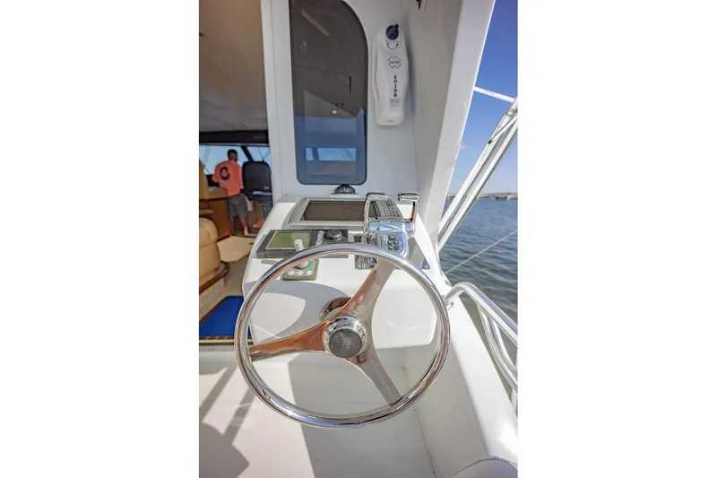 Slide: The Image of Steering wheel and controls of a 2003 Viking 65 EB yacht, overlooking the water. - 38