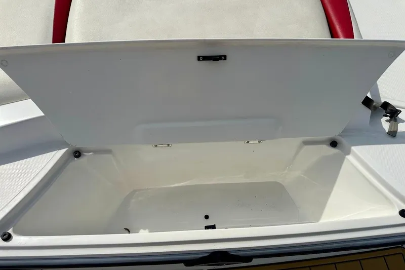 Slide: The Image of Open storage compartment in a 2012 Tigé R20 boat, featuring white and red interior. - 14