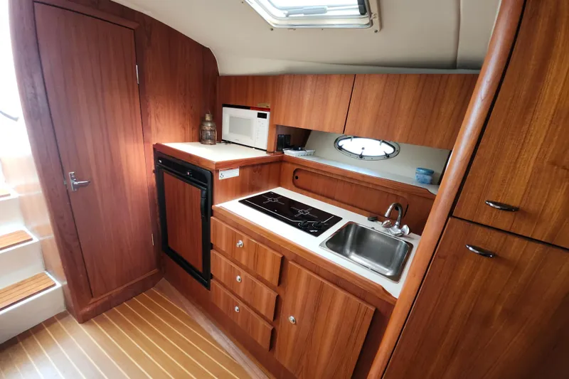 Slide: The Image of Interior of 2000 Tiara Yachts 3100 Open, featuring a compact kitchen with wood cabinetry. - 15
