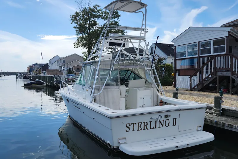 Slide: The Image of 2000 Tiara Yachts 3100 Open docked near waterfront homes under a clear sky. - 5