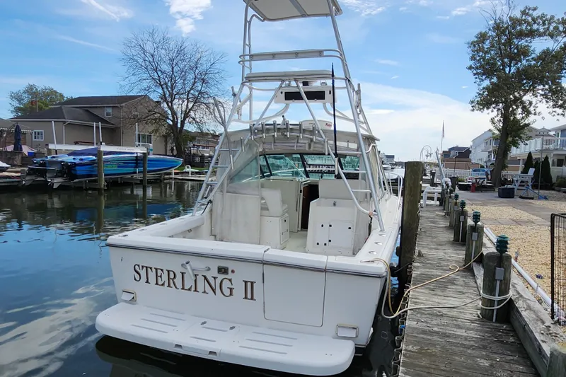 Slide: The Image of 2000 Tiara Yachts 3100 Open docked, rear view with tower and seating, named "Sterling II". - 6