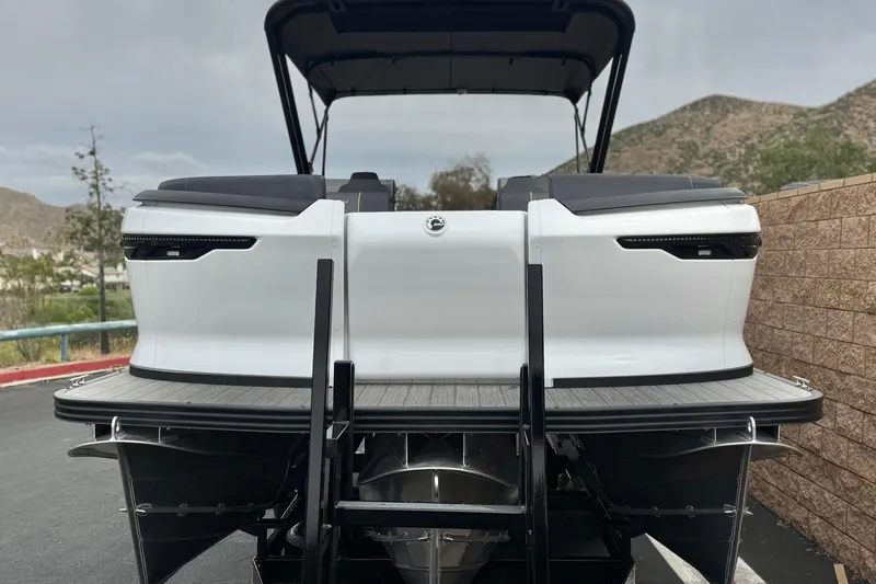 Slide: The Image of 2025 Manitou EXPLORE 24 pontoon boat, rear view, parked outdoors. - 2