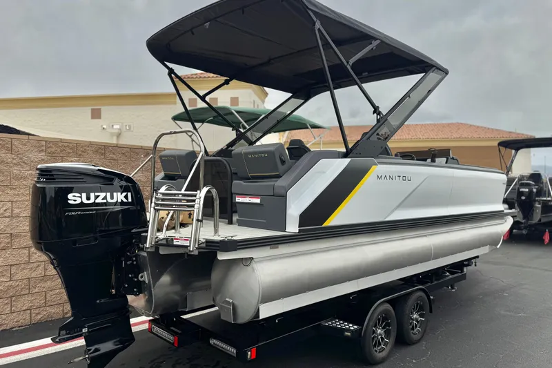 Slide: The Image of 2025 Manitou EXPLORE 24 pontoon boat with Suzuki outboard motor, parked on trailer. - 6