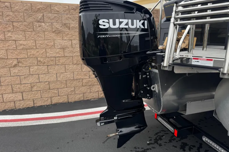 Slide: The Image of Suzuki outboard motor on 2025 Manitou EXPLORE 24 boat, parked on pavement. - 7