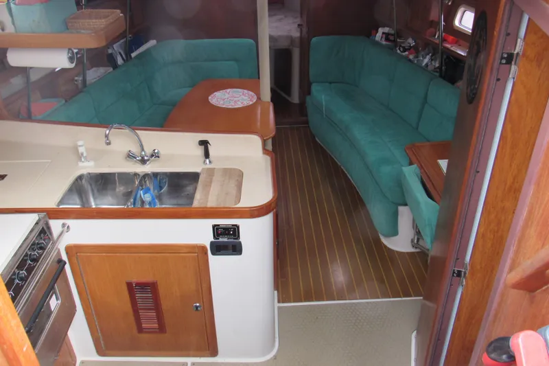 Slide: The Image of Interior of a 1999 Catalina 380 sailboat with teal seating and wooden accents. - 21