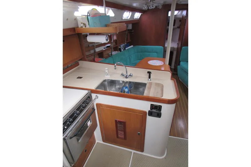 Slide: The Image of Interior of a 1999 Catalina 380 sailboat featuring a compact kitchen and seating area. - 23