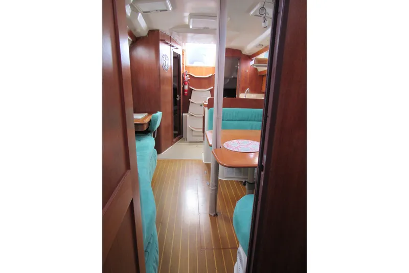 Slide: The Image of Interior of a 1999 Catalina 380 sailboat with wood paneling and teal seating. - 28