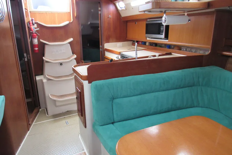 Slide: The Image of Interior of 1999 Catalina 380 sailboat with teal seating and wooden cabinetry. - 29