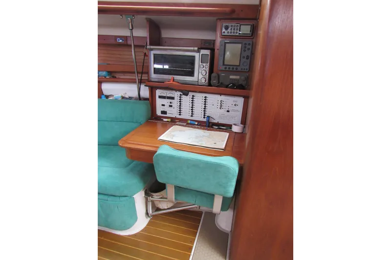 Slide: The Image of Navigation station inside a 1999 Catalina 380 sailboat with teal seating and electronic equipment. - 30