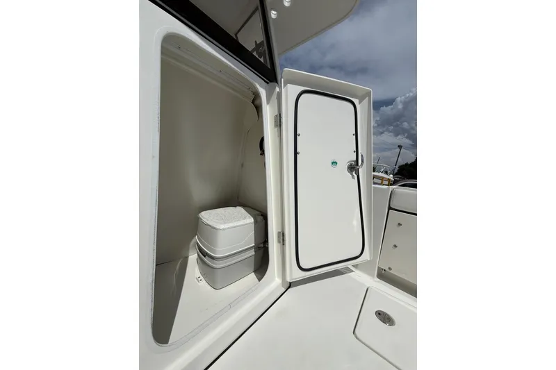 Slide: The Image of 2026 World Cat 235 TE boat interior with open storage compartment and portable toilet. - 12