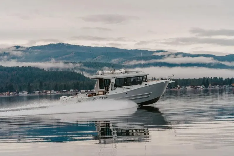 The Image of 2026 KingFisher 38 GFX boat cruising on a serene lake with misty mountains. - 1
