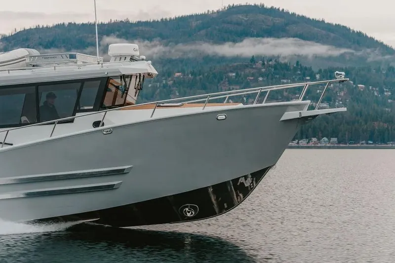 Slide: The Image of 2026 KingFisher 38 GFX boat cruising on a lake with forested hills in the background. - 2