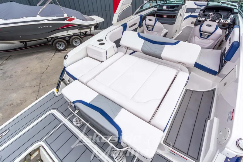 Slide: The Image of 2021 Chaparral 267 SSX boat interior with white and blue seating, docked beside another boat. - 13