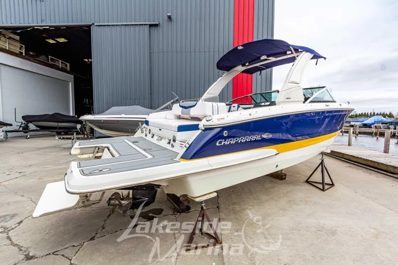 Slide: The Image of 2021 Chaparral 267 SSX boat in marina, blue and yellow design, docked outdoors. - 3